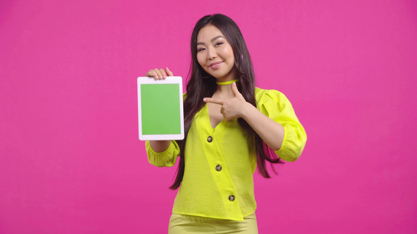 niña kazakh sosteniendo tableta digital con pantalla verde aislada en rosa
  - Imágenes, Vídeo