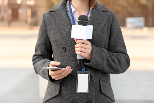Gyönyörű újságíró mikrofonnal a szabadban - Fotó, kép
