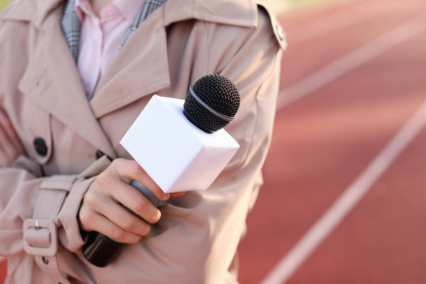 Belo repórter com microfone no estádio, close-up
 - Foto, Imagem