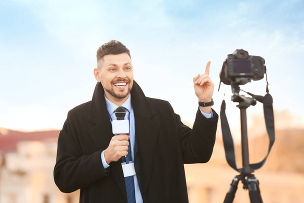Άνδρας δημοσιογράφος με μικρόφωνο σε εξωτερικούς χώρους - Φωτογραφία, εικόνα