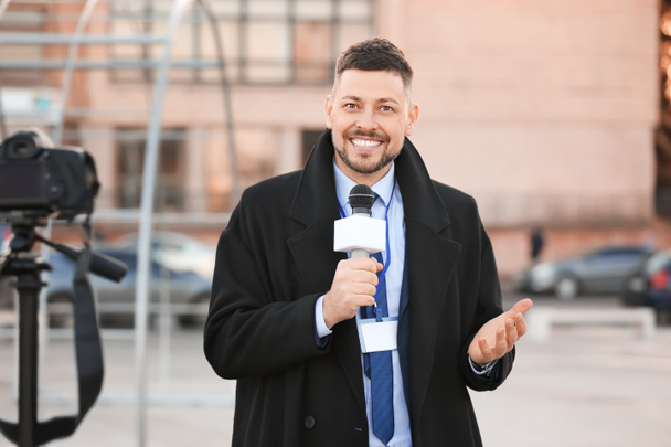 Jornalista masculino com microfone ao ar livre
 - Foto, Imagem