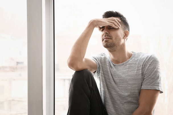Депрессивный молодой человек у окна
 - Фото, изображение