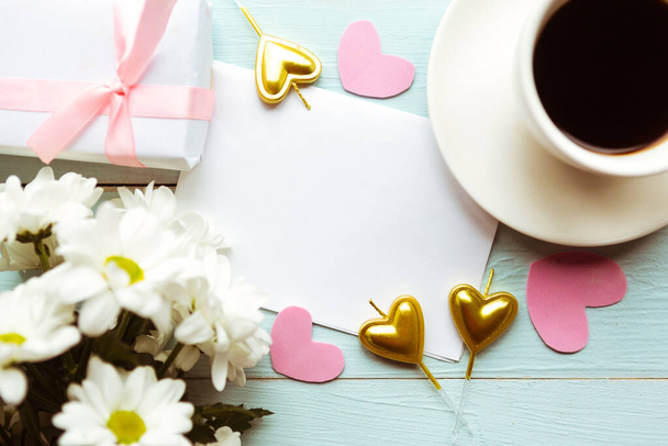Επίπεδη φωτογραφία lay με λευκά λουλούδια, φλιτζάνι καφέ και κουτί δώρου. Όμορφη Γάμος, Ημέρα του Αγίου Βαλεντίνου ή την Ημέρα της Μητέρας ευχετήρια κάρτα - Φωτογραφία, εικόνα