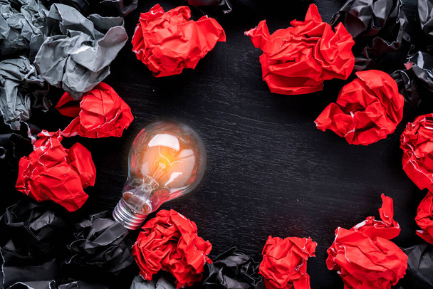 Kreativität Ideen Konzept mit Glühbirne und schwarz-rotem Farbpapier zerknüllte Müllkugel - Foto, Bild