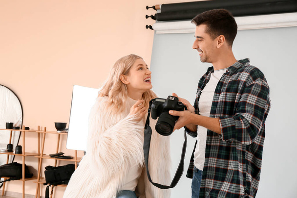 Professional photographer showing pictures to model in studio - Foto, Bild