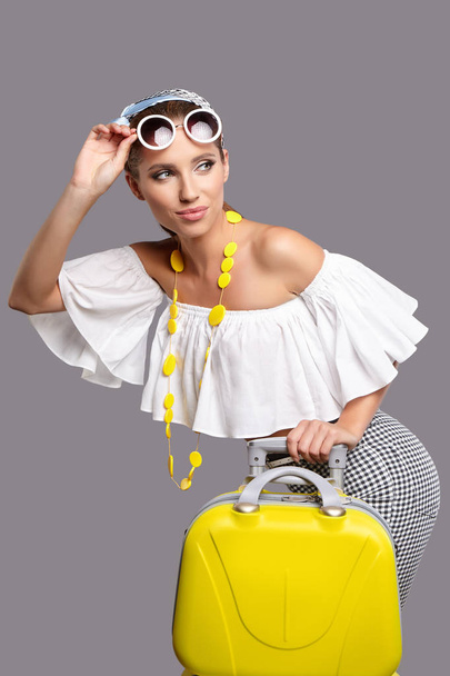 Portrait of young woman wearing shawl standing with yellow travel bag - Foto, Imagem