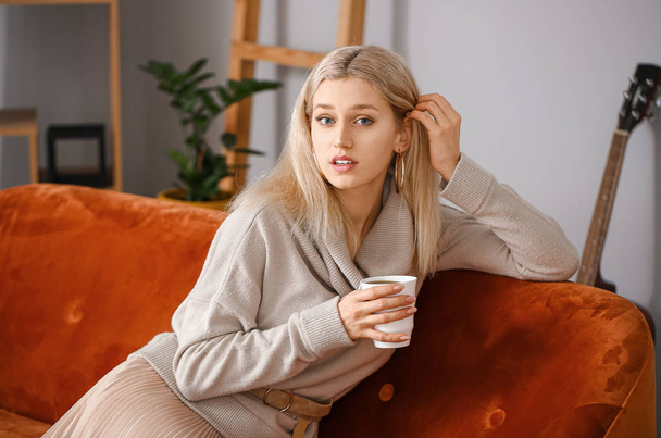 Hermosa mujer joven en suéter caliente beber té en casa
 - Foto, Imagen