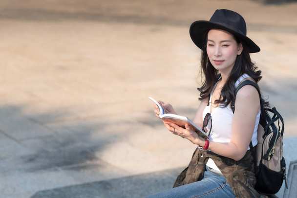 Belle femme touristique asiatique regardant le guide de voyage pour rechercher l'emplacement du point de repère. Voyages vacances en été
 - Photo, image