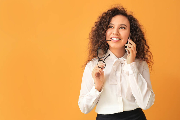 Jonge Afro-Amerikaanse zakenvrouw praten per telefoon op kleur achtergrond - Foto, afbeelding