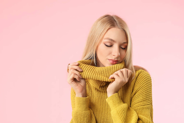 Young woman in warm sweater on color background - Фото, зображення