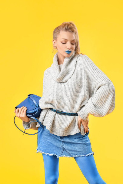 Νεαρή γυναίκα με δημιουργικό μακιγιάζ και ζεστό πουλόβερ σε φόντο χρώμα - Φωτογραφία, εικόνα