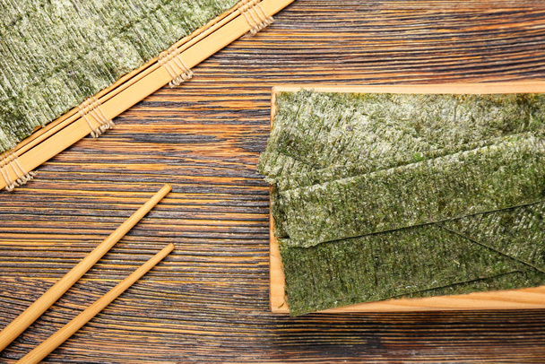 Tasty seaweed sheets and chopsticks on table - Foto, afbeelding