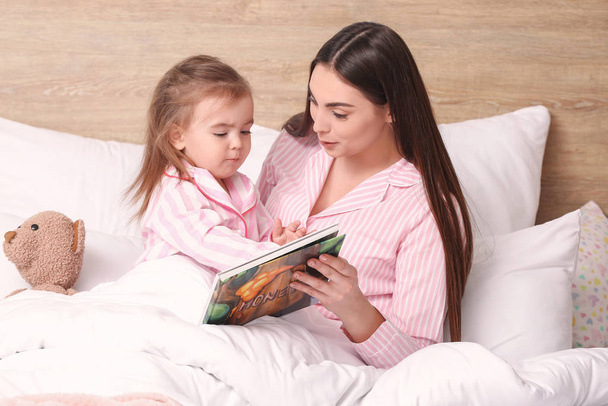 Anne ve küçük kızı evde yatmadan önce hikaye okuyor - Fotoğraf, Görsel