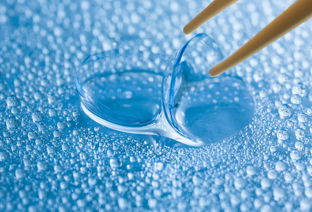 Lentes de contato e pinças no fundo de cor com gotas de água, close-up
 - Foto, Imagem
