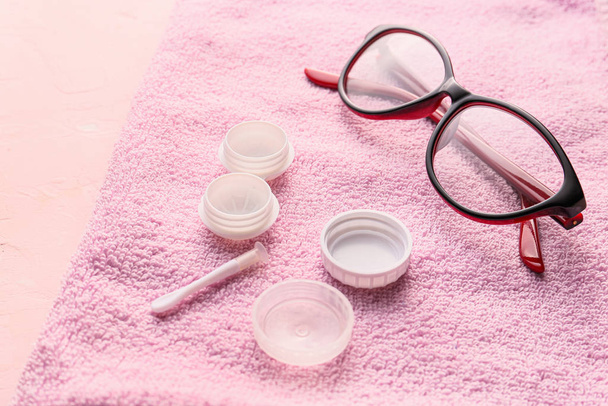 Óculos e recipiente para lentes de contato na toalha
 - Foto, Imagem