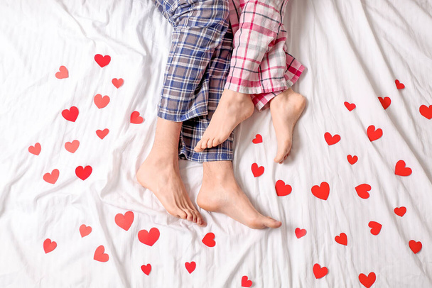 Young couple with red hearts lying in bed, top view - Foto, immagini