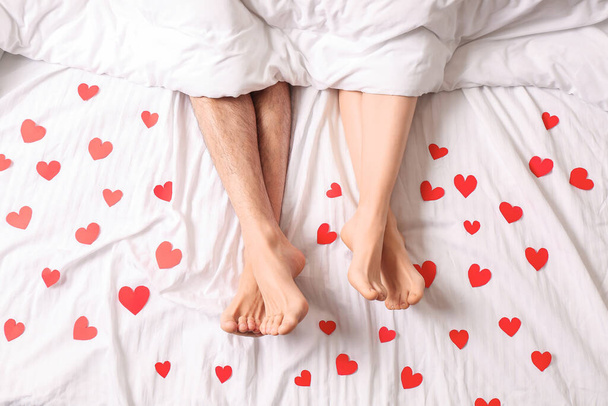 Young couple with red hearts lying in bed, top view - Foto, Bild