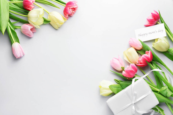 Όμορφα λουλούδια και δώρο για την Ημέρα της Μητέρας σε λευκό φόντο - Φωτογραφία, εικόνα