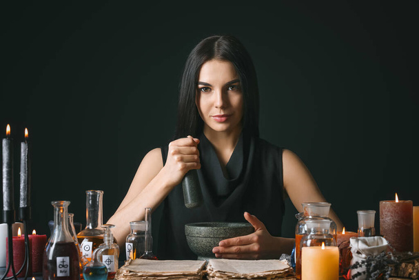 Vrouwelijke alchemist maken toverdrank op donkere achtergrond - Foto, afbeelding