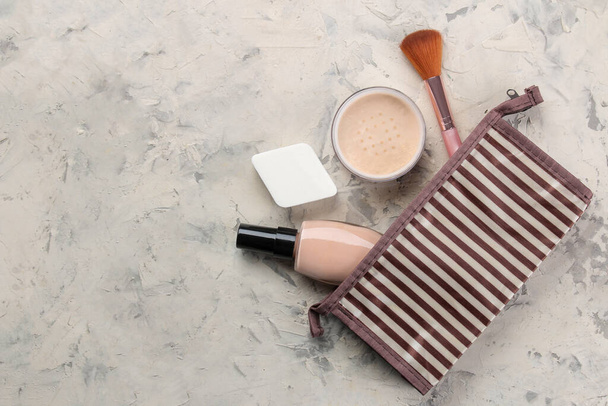 Make-up kit. Vrouwen cosmetica in een cosmetische zak en make-up borstels op een lichte betonnen achtergrond. Vrouwen dingen. bovenaanzicht - Foto, afbeelding