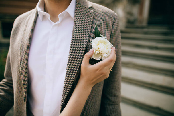  The bride touches the groom's shoulder and his white peony boutonniere. Love concept - Fotoğraf, Görsel