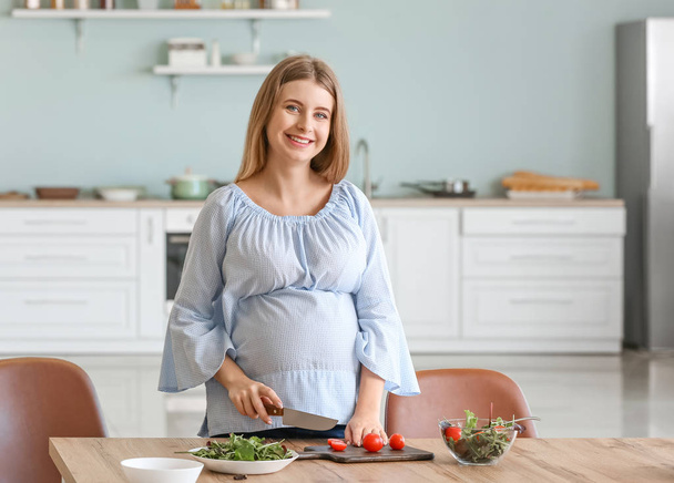 Schöne junge schwangere Frau kocht in Küche - Foto, Bild