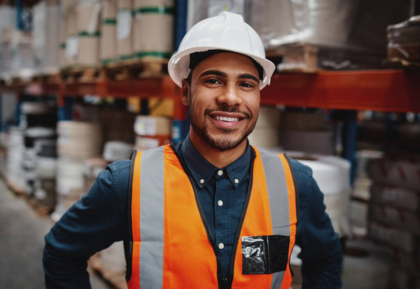 Happy warehouse manager standing in factory wearing white helmet and orange safety vest looking at camera smiling - Photo, image