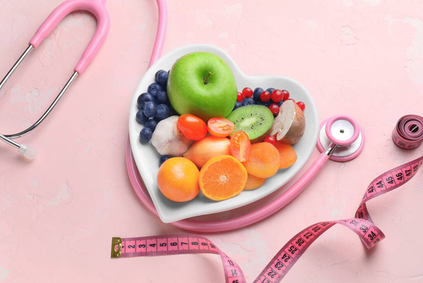 Тарелка со здоровыми продуктами, стетоскоп и измерительная лента на цветном фоне
 - Фото, изображение