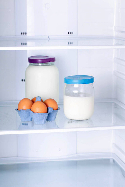 Eggs and milk in the refrigerator, vertical - Foto, Imagen
