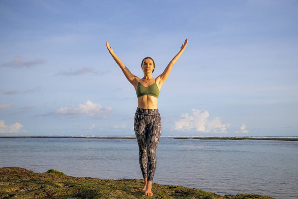 旅行生活。海の前のビーチで腕を上げて興奮した若い女性。自由とエネルギー。オーシャンビュー。コピースペース。バリ島のメラスティビーチ - 写真・画像