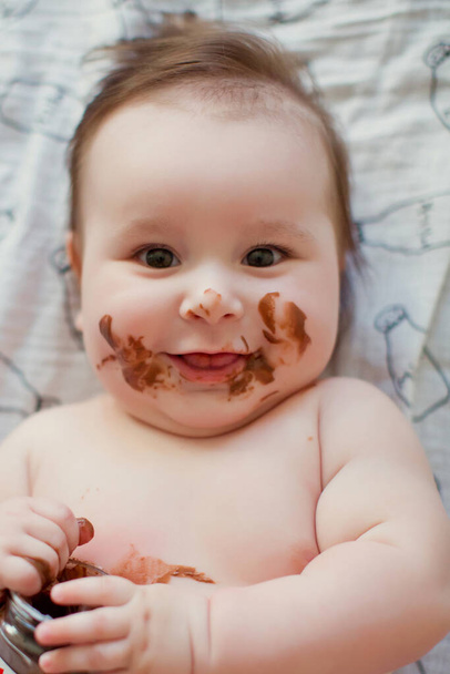 可愛い赤ちゃんがチョコレートペーストを食べる。チョコレートの汚い顔 - 写真・画像