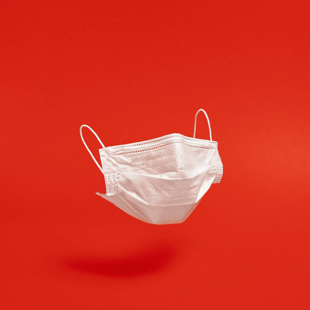 Surgical face mask on red background. Minimal medical concept. Medical equipment - Foto, afbeelding