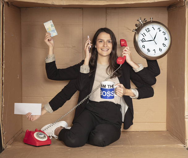 многозадачная деловая женщина, сидящая в картонном офисе, делая много вещей одновременно
 - Фото, изображение