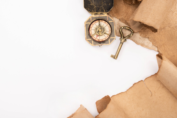 bovenaanzicht van vintage sleutel, kompas en oud papier geïsoleerd op wit - Foto, afbeelding