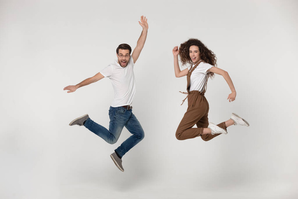 Full length joyful young man and happy woman jumping high. - Φωτογραφία, εικόνα