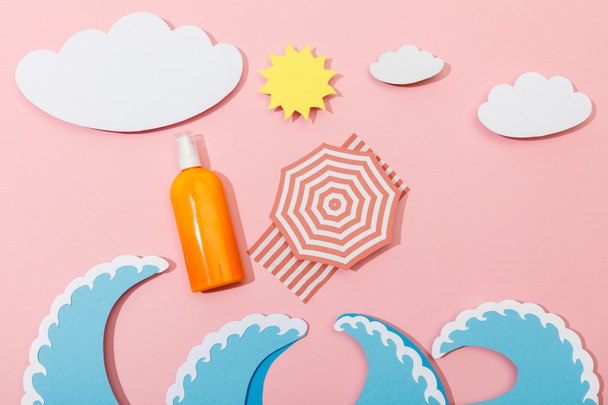 Top view of paper cut summer beach with dispenser bottle of sunscreen on pink background - Фото, изображение