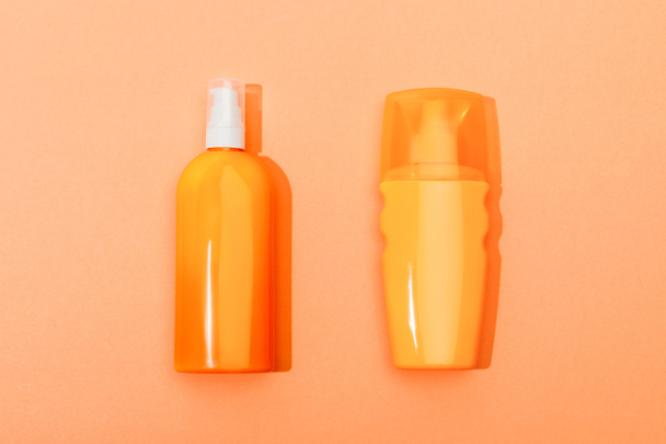Top view of dispenser bottles of sunscreen on orange background - Photo, Image