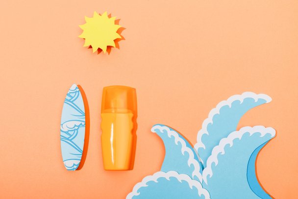 Vue du dessus du distributeur bouteille de crème solaire avec du papier coupé vagues de mer, soleil et planche de surf sur orange
  - Photo, image