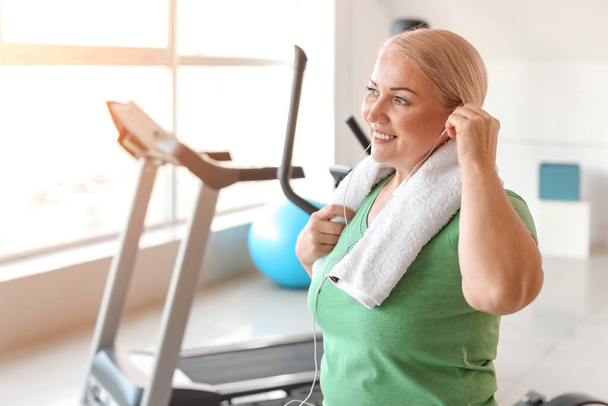 Sporty mature woman listening to music in gym - Photo, image