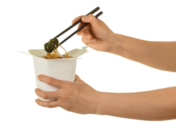 Female hand takes of sticks, spicy Chinese noodles from wok box, isolated on white background - Zdjęcie, obraz