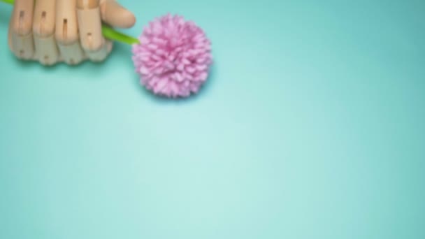 wooden hand holding artificial flowers. blue background - Metraje, vídeo