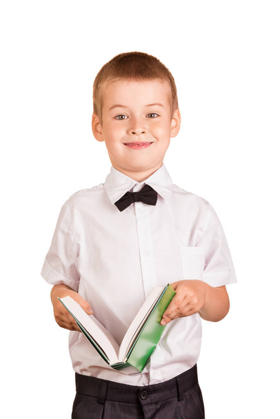 Pupil in white shirt and bow tie is holding an open book in his hands, isolated on white background - Photo, Image