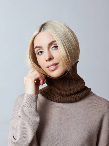 Beautiful blonde woman with a Snood Scarf around her neck. Girl in spring clothes, warm sweater - Photo, image
