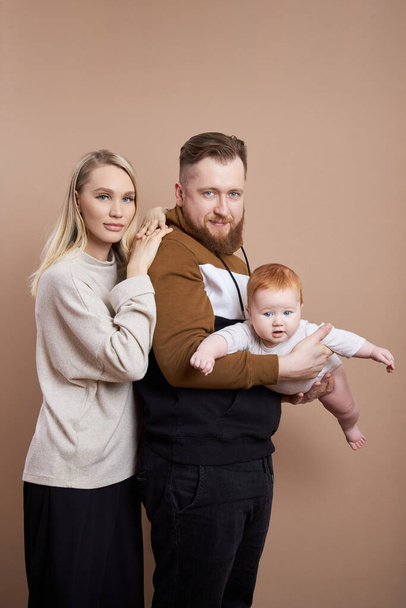 Man and a woman hold a baby in their arms. Portrait of a married couple after the birth of a child. Young family - Foto, Bild