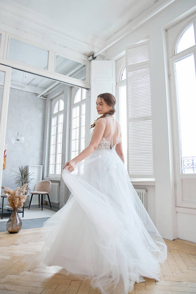 Brown-haired girl in a beautiful white wedding dress. A woman bride is waiting for the groom before the wedding - Photo, image