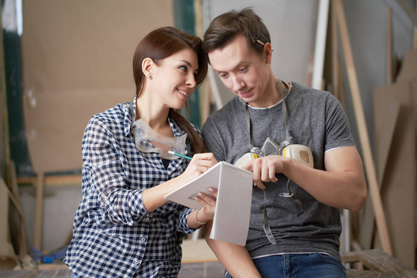 Happy male and woman joiners with notebook in their hands - Photo, Image