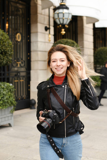 jonge blonde vrouw lopen in de stad met camera. - Foto, afbeelding