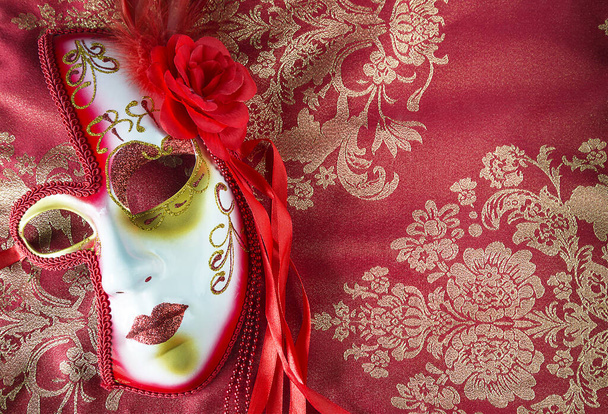 Όμορφη βενετσιάνικη μάσκα καρναβαλιού σε όμορφο κόκκινο και χρυσό ύφασμα - Φωτογραφία, εικόνα