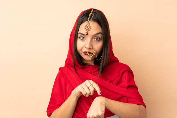 Young Indian woman isolated on beige background making the gesture of being late - Fotografie, Obrázek