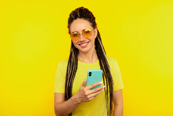 Щаслива усміхнена жінка з яскравим телефоном в жовтій студії
. - Фото, зображення